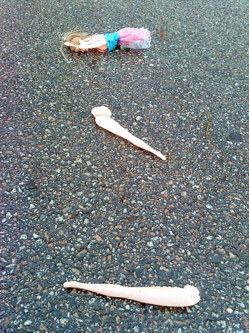 photo d'une poupée détruite sur la route, les jambes séparées de son corps