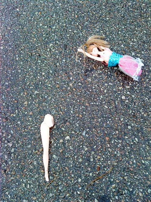 photo de dessus d'une poupée sans jambe sur une route